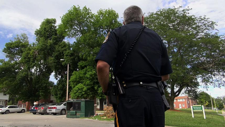 The back of a police officer walking through a townhome complex
